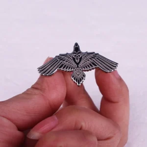 Hand hält Wikinger Brosche mit fliegendem Raben - nordisches Wikinger Schmuckstück